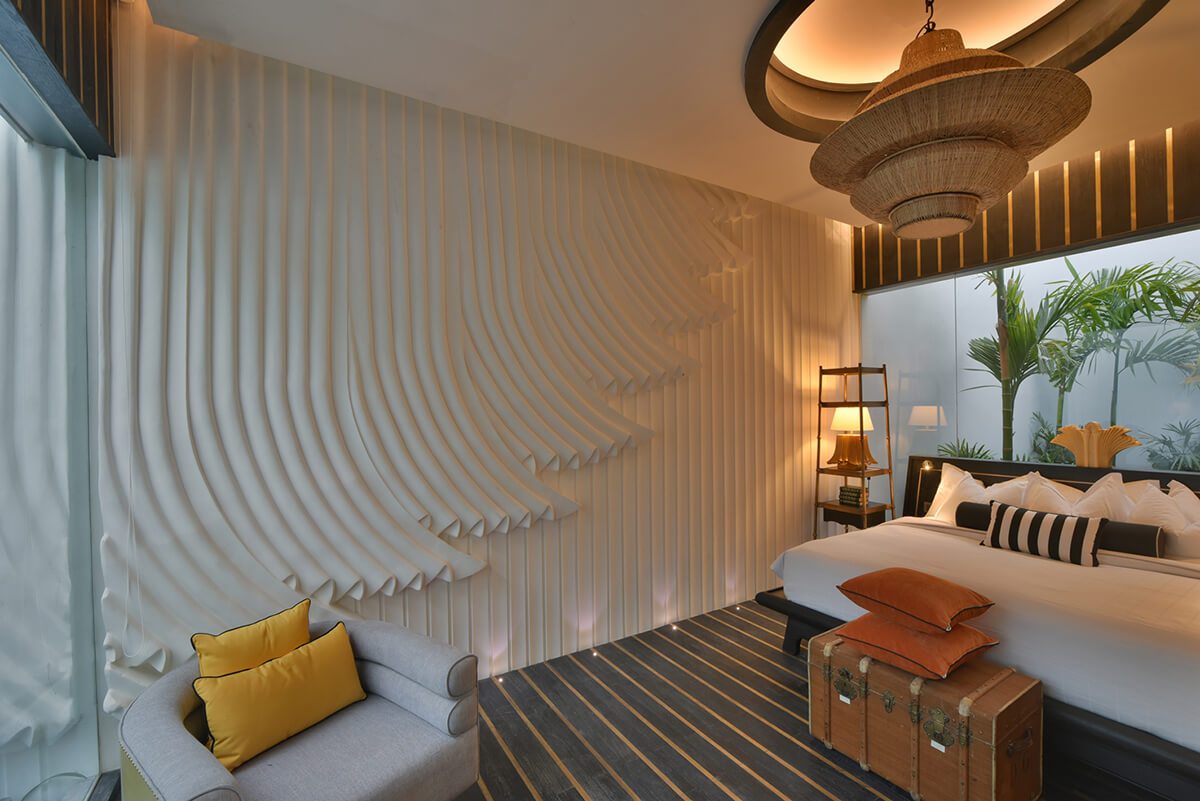 Inspired bedroom designed by architect Bill Bensley in Cambodia with textured walls and low lighting