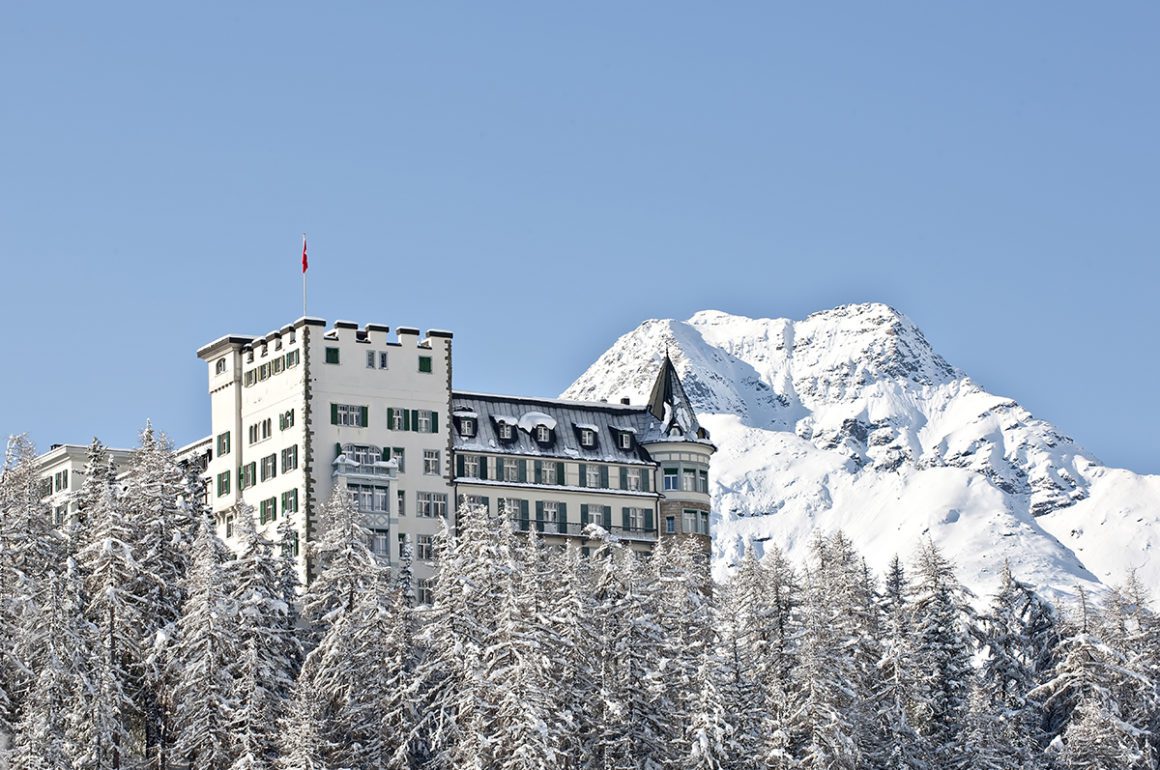 Waldhaus Sils five star swiss hotel rising up from the trees in front of the snowy mountains in Winter