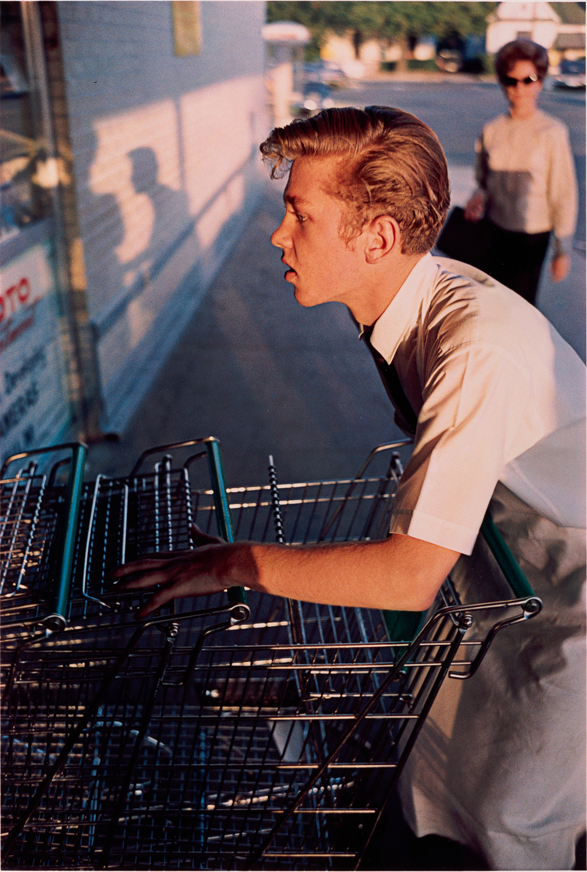 First colour photograph of a young clerk pushing a trolley by William Eggleston, Memphis