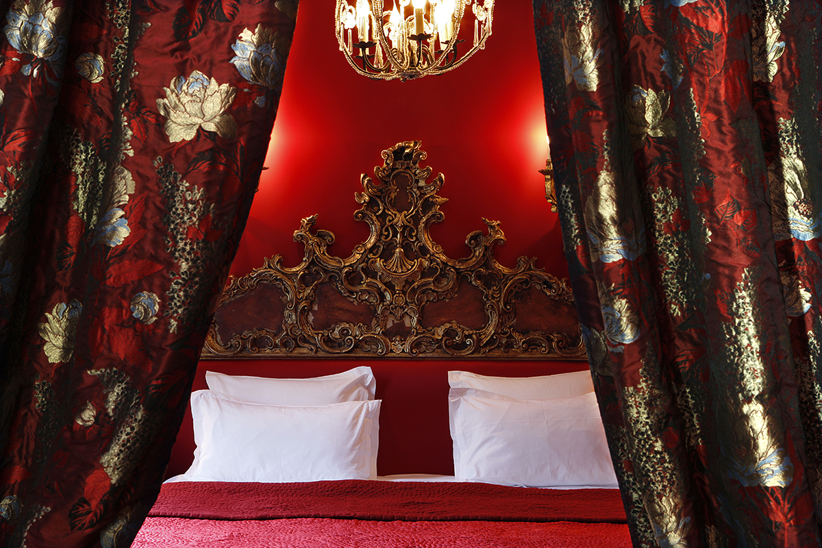 red and gold luxury bedroom with decadent silk curtains and chandelier 