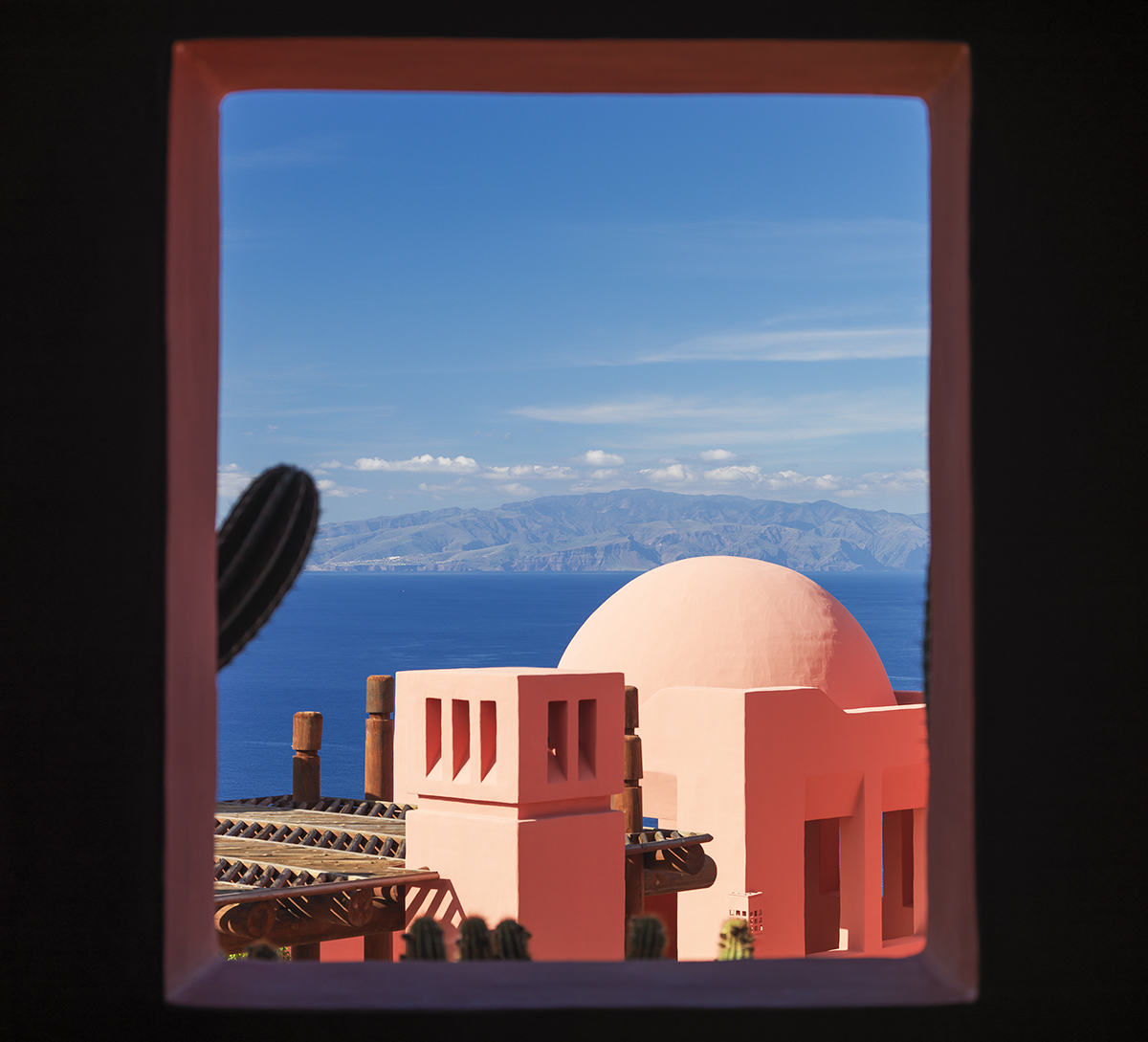 Pink domed roof of a building and the ocean seen through a window