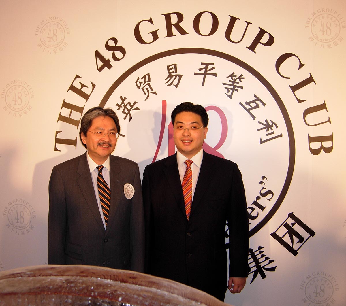 Two Asian business men standing in front of 48 Group Club sign