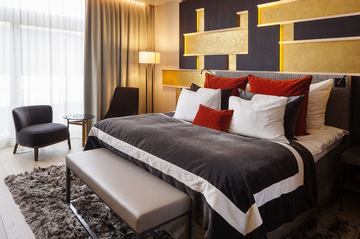 Luxury hotel bedroom with huge double bed, gold wall and plush linens