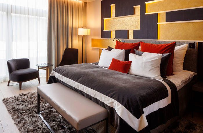 Luxury hotel bedroom with huge double bed, gold wall and plush linens