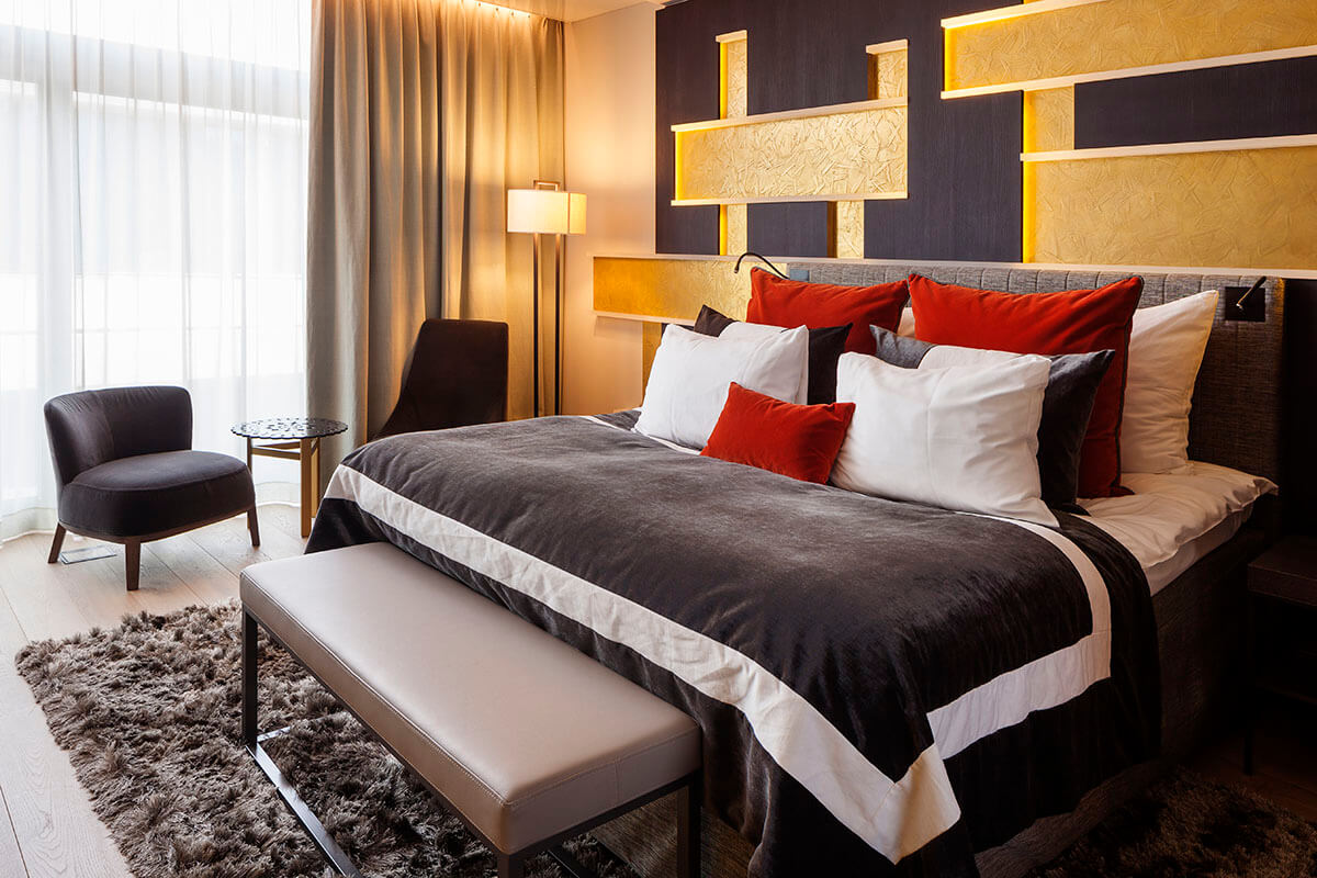 Luxury hotel bedroom with huge double bed, gold wall and plush linens