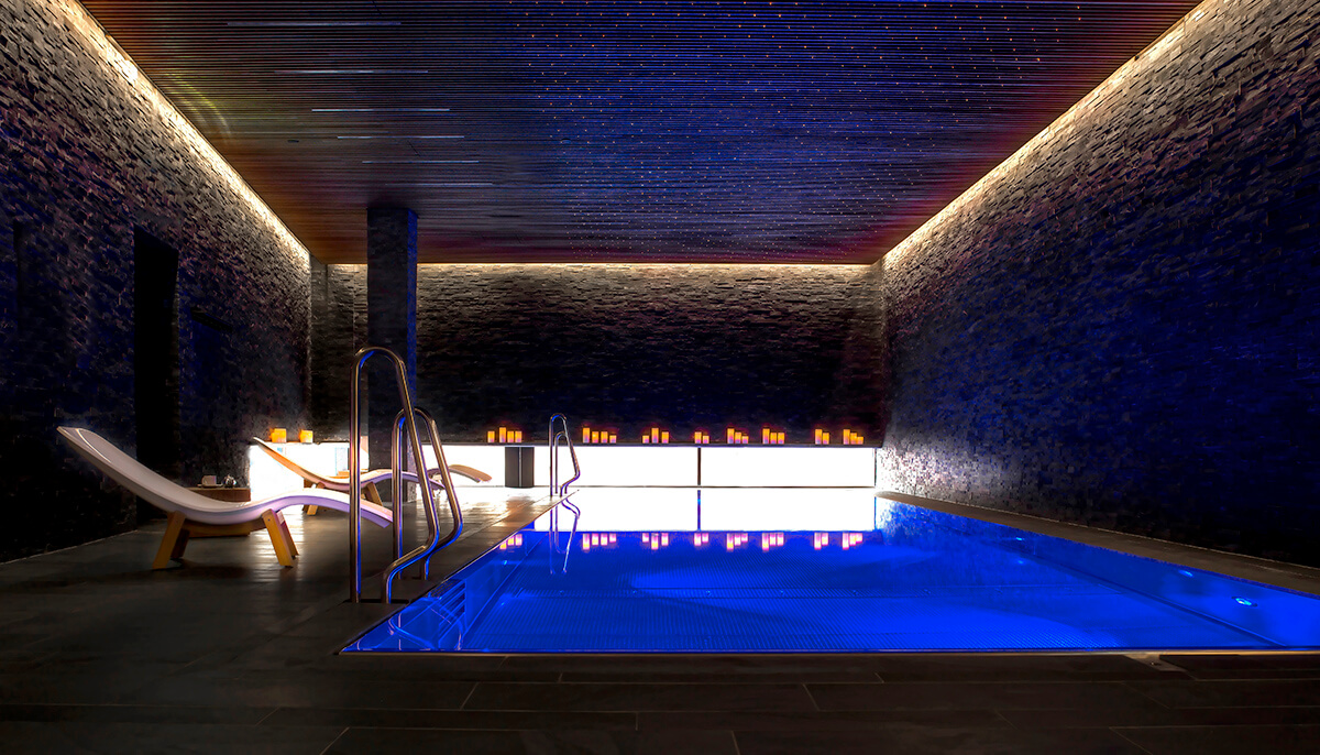 luxury concrete spa with indoor pool and underwater lighting
