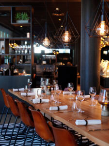 smart restaurant with large table laid for dining and industrial style lighting