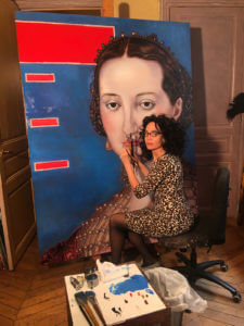 Artist Mouna Rebeiz at work on a large painting of a woman's face