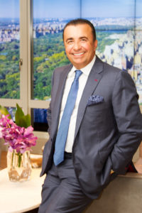 Portrait of renowned real estate broker Gennady Perepada in a suit and tie in front of New York backdrop