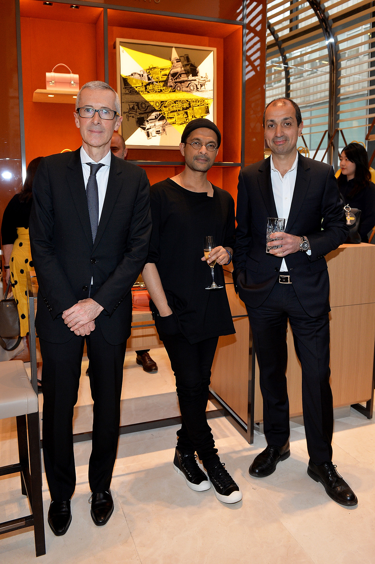 Moynat's CEO Guillaume Davin, Creative Director, Ramesh Nair and LUX Editor-in-Chief Darius Sanai holding flutes of champagne in Moynat shop