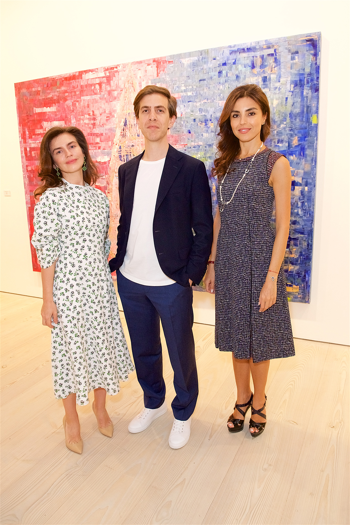 Persian artist Sassan Behnam-Bakhtiar poses in front of his painting with his wife and Nina Moaddel at gallery opening