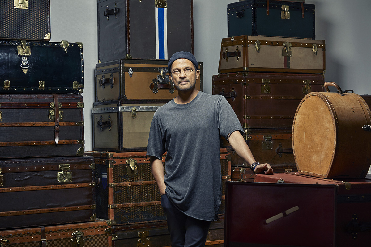Hipster man standing in room filled with old style luggage