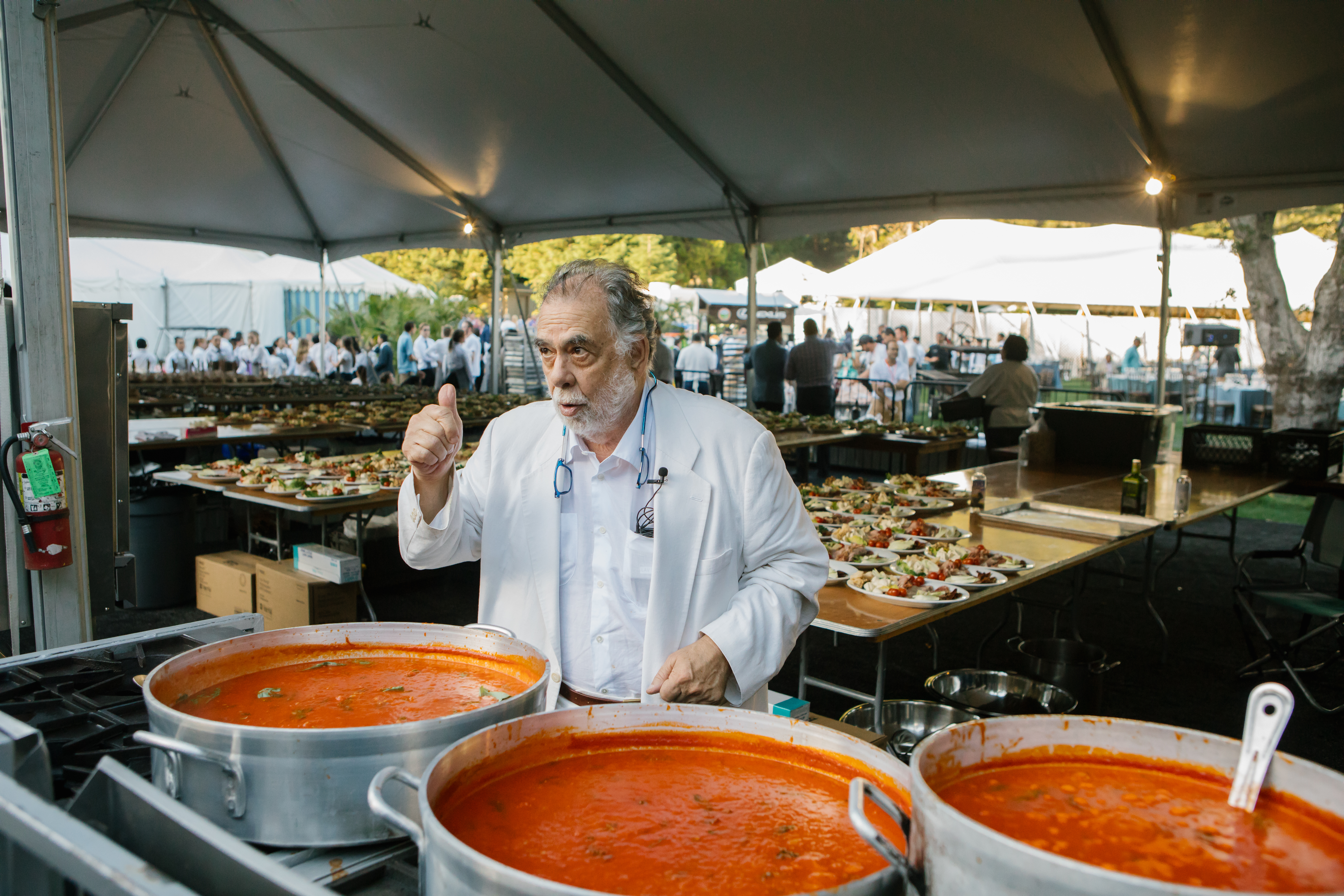 Man stands behind big silver bowls of tomato sauce