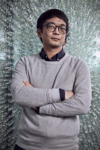 Man wearing glasses with arms folded in front of crystal background