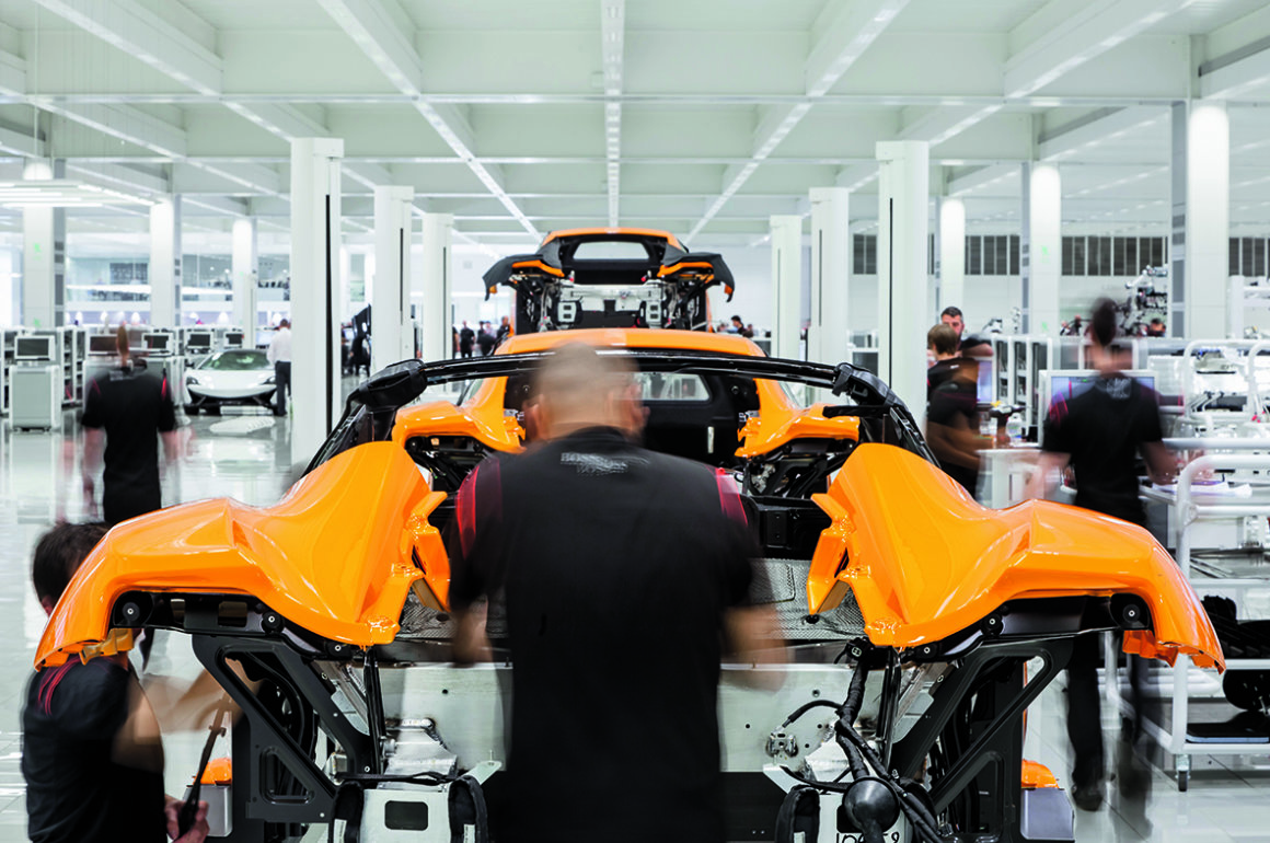 yellow sportscar manufacturing process in workshop with engineer working on engine