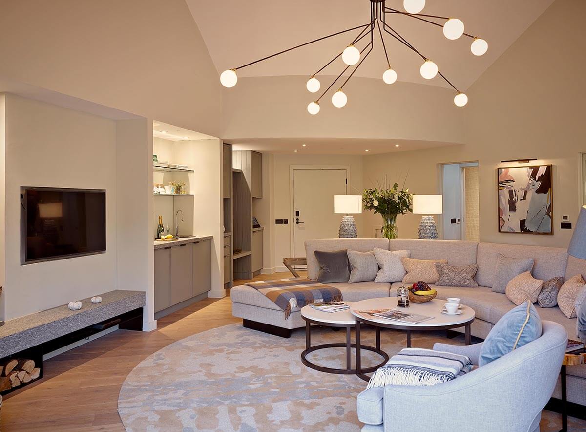 contemporary interiors of a sitting room cross kitchen decorated in pale creams and purples with a large sofa and modern light fitting