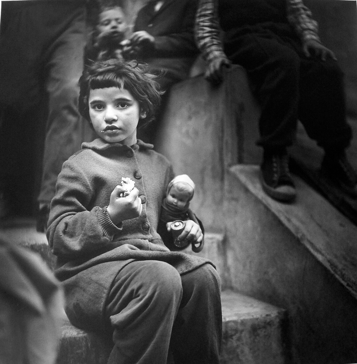 black and white photograph of little girl holding dolly on a step