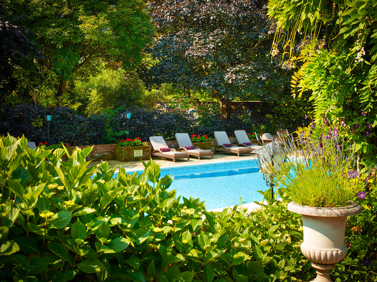Glimpse of a pretty outdoor swimming pool surrounded by plush sun loungers