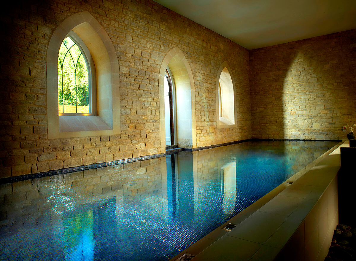 luxury indoor pool surrounded by light stone walls