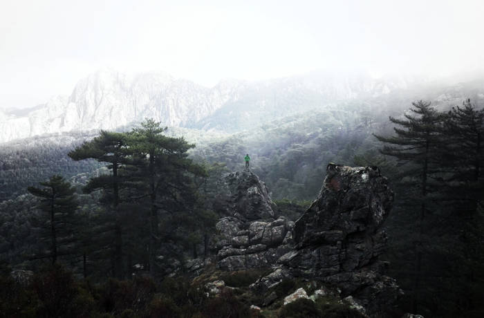 lone traveller stands on the top of stones overlooking mountains