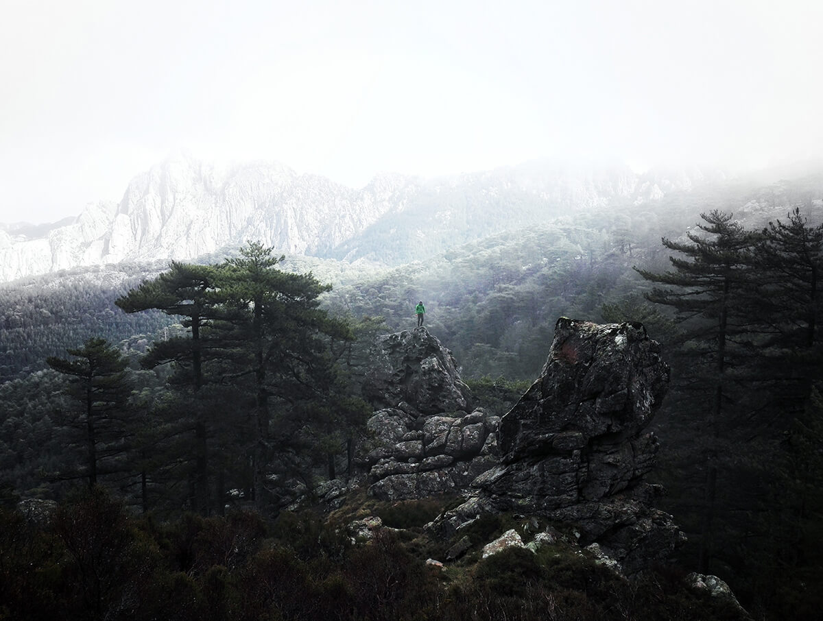 lone traveller stands on the top of stones overlooking mountains