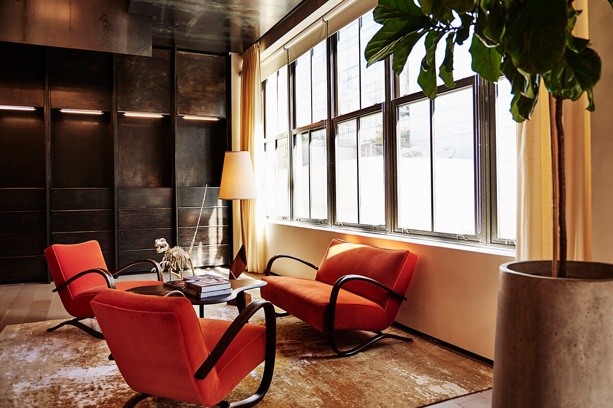 stylish contemporary interiors of a lounge space with orange chairs, big glass windows and wooden detailing