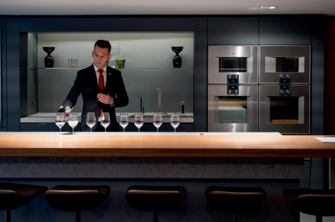 Sommelier pouring wine in modern style kitchen