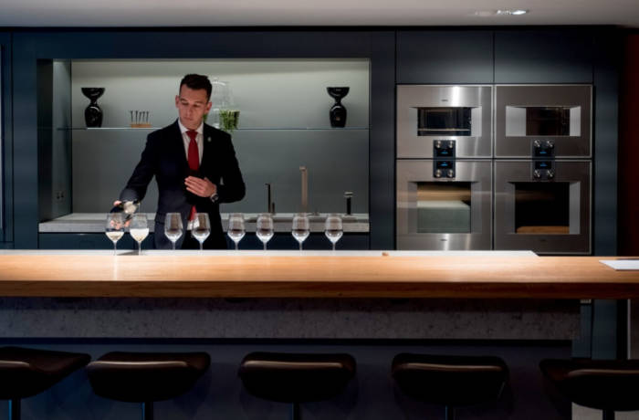 Sommelier pouring wine in modern style kitchen