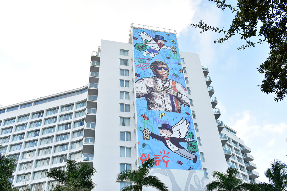 Large scale mural by Alec Monopoly on the side of a building in Miami's design district