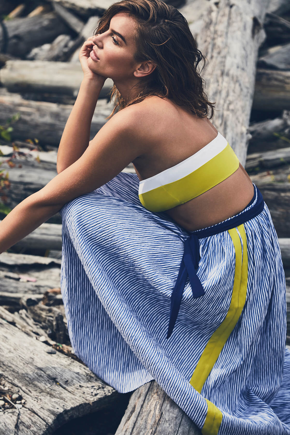 Model poses in yellow bandana bikini top and blue striped full length skirt