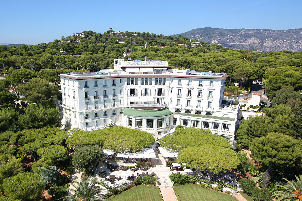 large grand mansion building nestled into lush green trees 