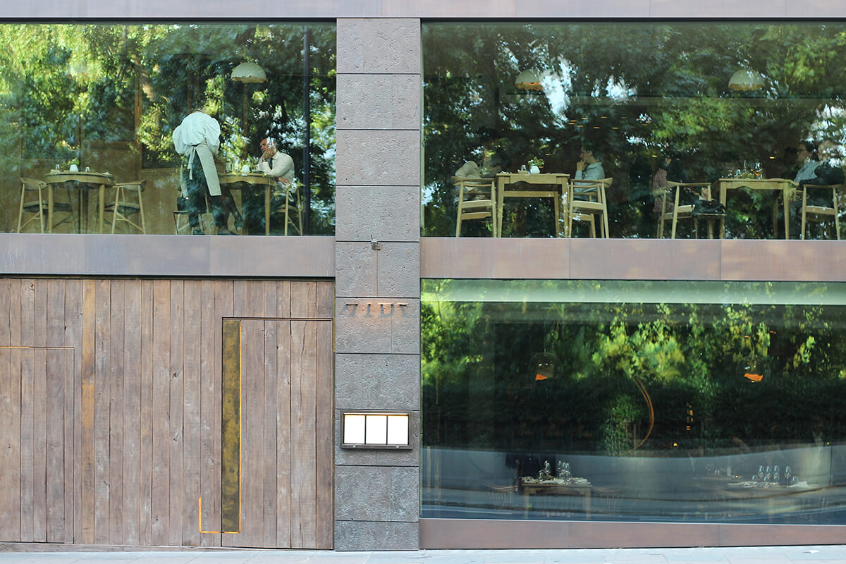 sleek exterior of HIDE restaurant with glass windows reflecting the trees of the Green Park opposite