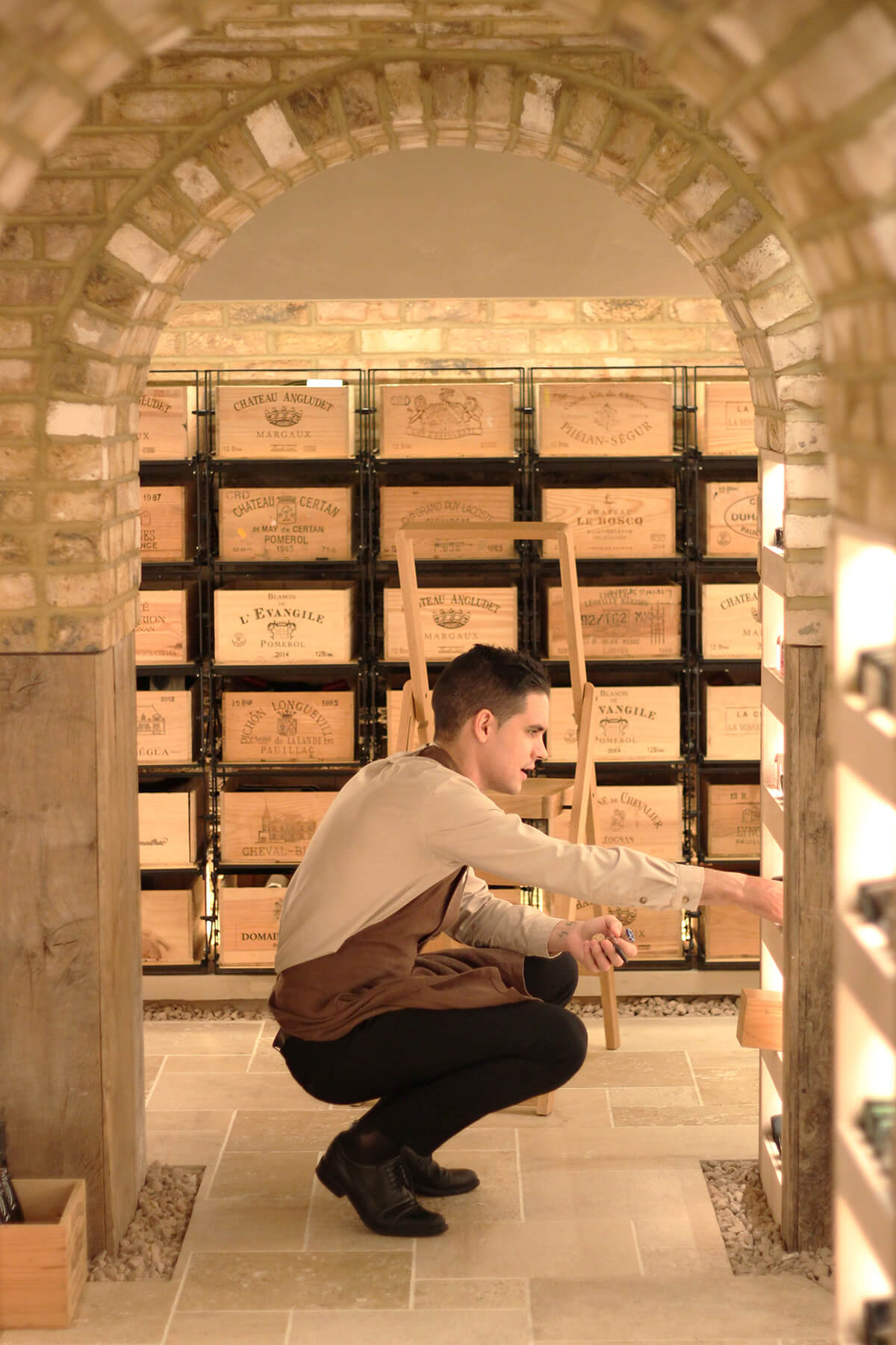 Waiter crouching to lift bottle from the wine cellar at hide restaurant
