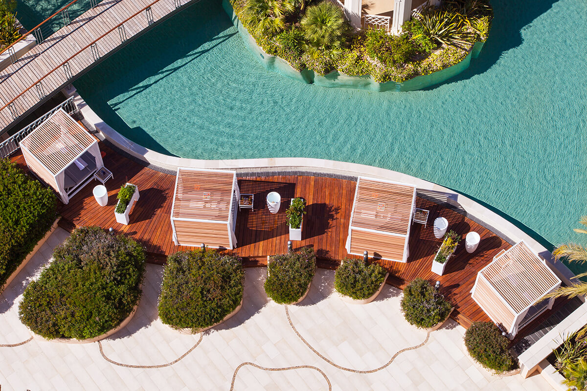Aerial shot of luxury swimming pool surrounded by wooden decking and cabanas