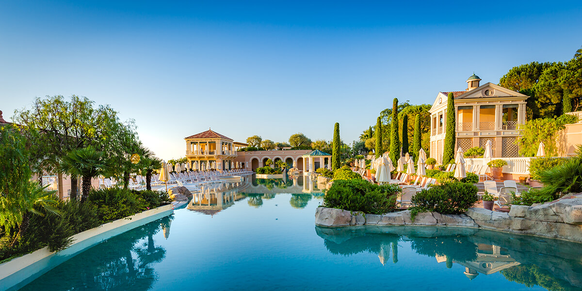 luxury swimming pool with arched bridge at one end, surrounded by lush greenery