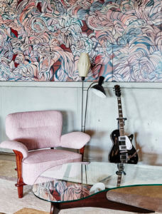 colourful contemporary interiors with pink arm chair, patterned pink wall and an electric guitar