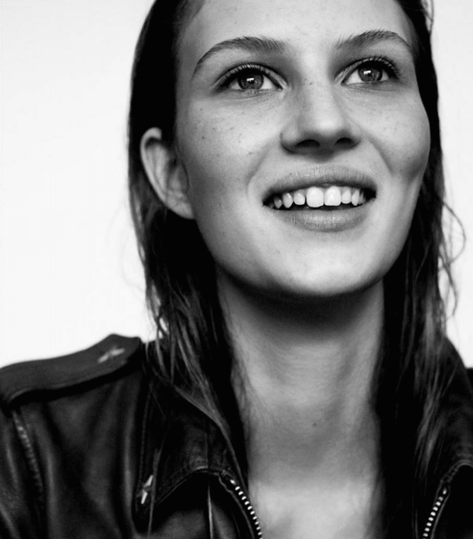 close up black and white headshot of model smiling in leather jacket