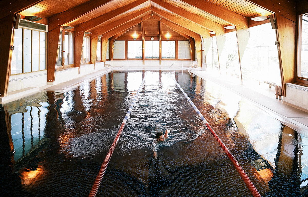 large indoor pool with swimmer mid-front crawl in the middle lane