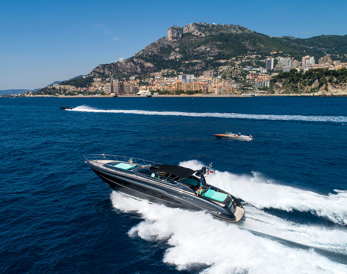 Speed boats travelling across the ocean with white spray spitting out behind them and the coast in the background