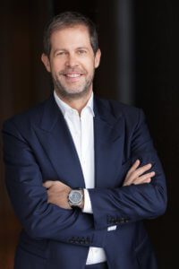 Headshot of business man wearing a blue suit jacket and white shirt