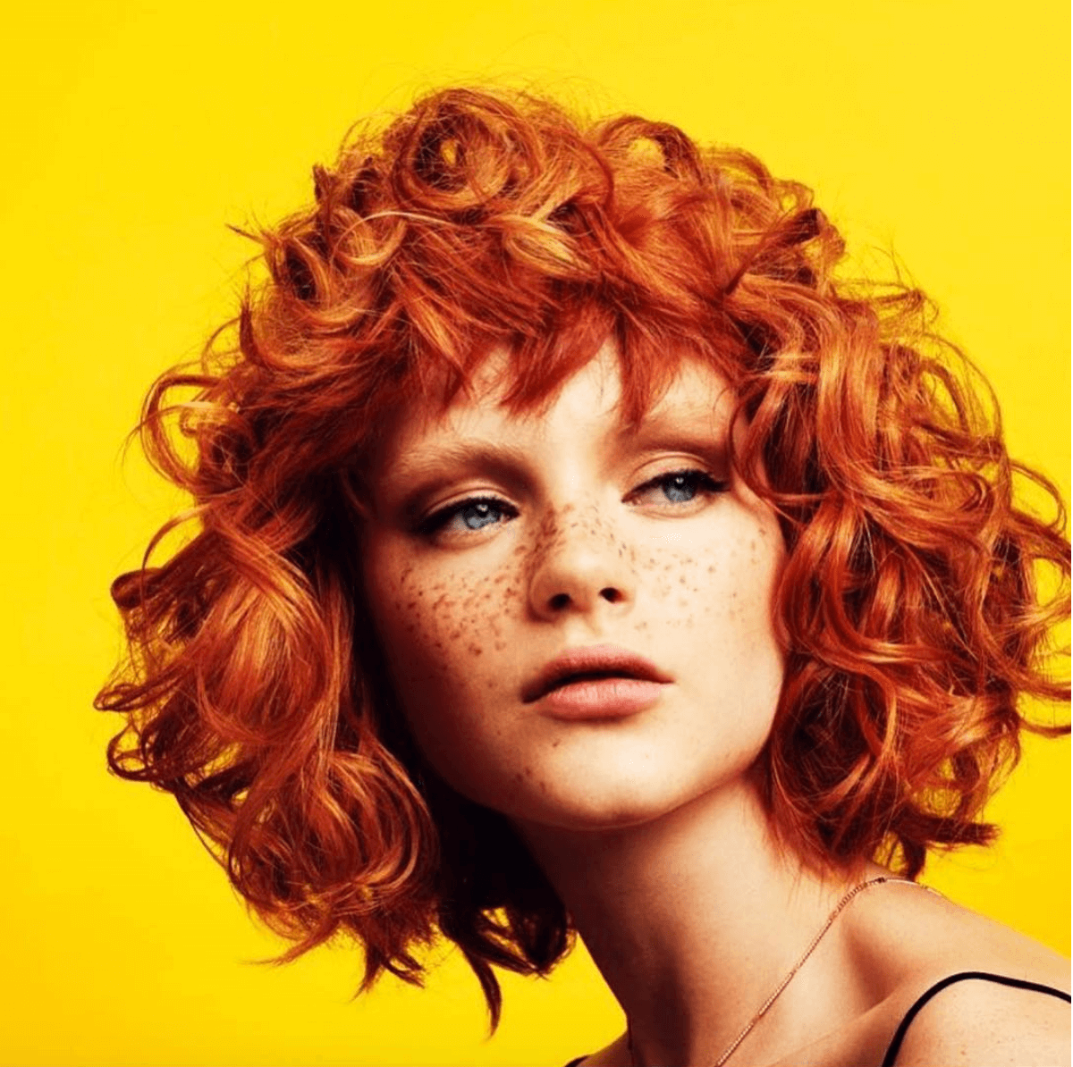 striking red haired model poses in front of yellow background