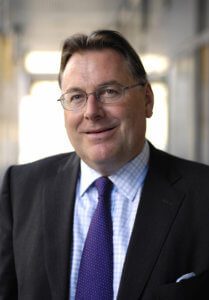 Portrait of a man wearing a suit with glasses and a purple tie