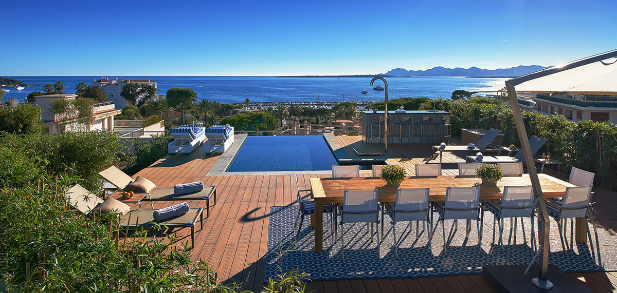 Luxurious rooftop swimming pool with wooden decking and views of the ocean on the horizon
