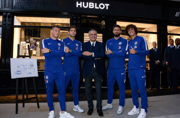 Chelsea FC football players in their blue tracksuits standing outside of a Hublot shop front with Ricardo Guadalupe
