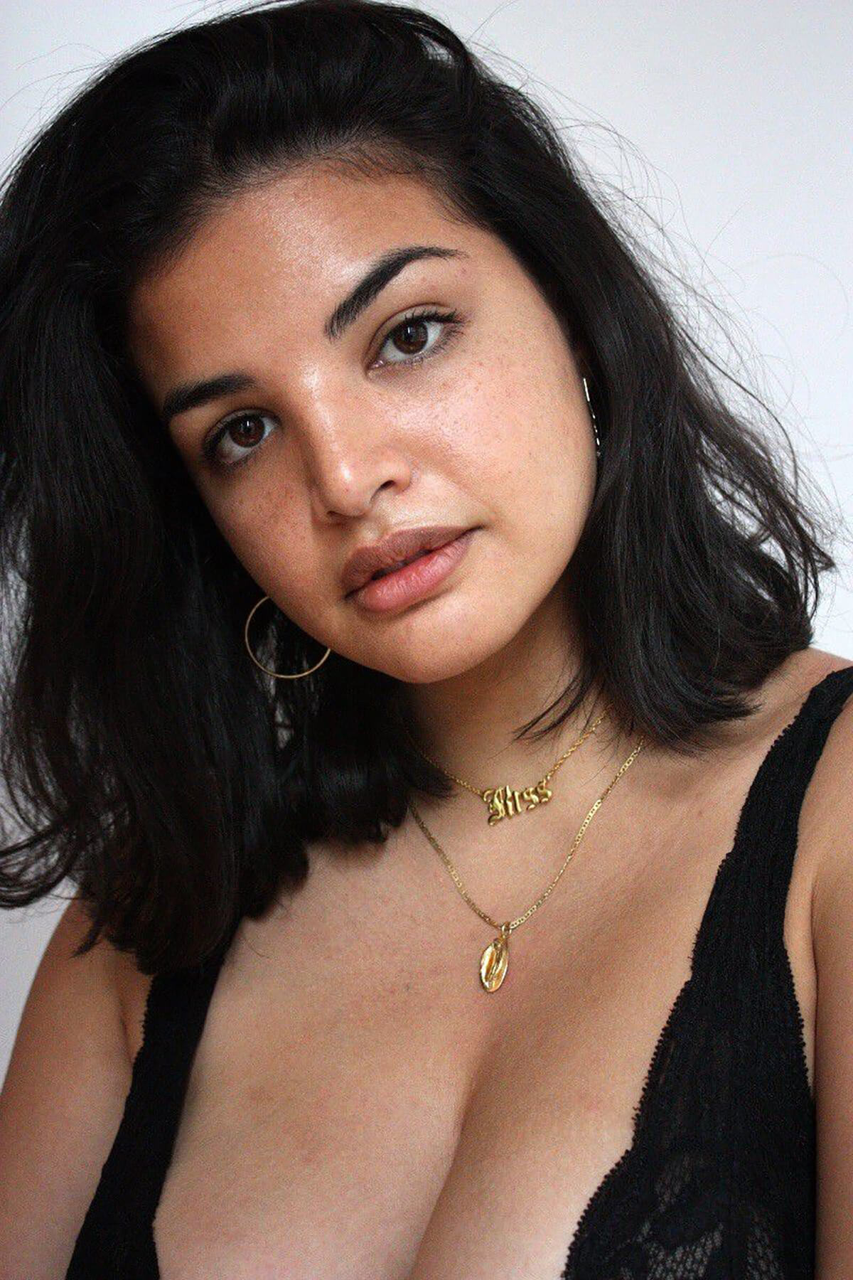 Model posing in black bra with gold necklaces