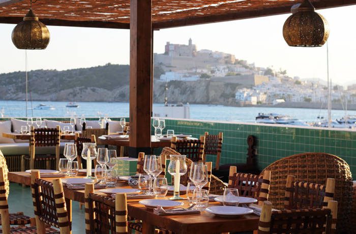 Rooftop restaurant with tables laid ready for dining and views of the sea and a fort in the distance