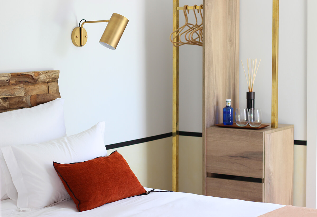 detail image of luxury bedroom with gold overhead lamp, plus pillow and gold railing