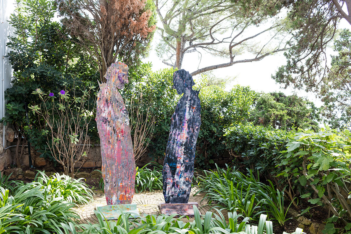 Two colourful sculptures of men standing in a lush green garden