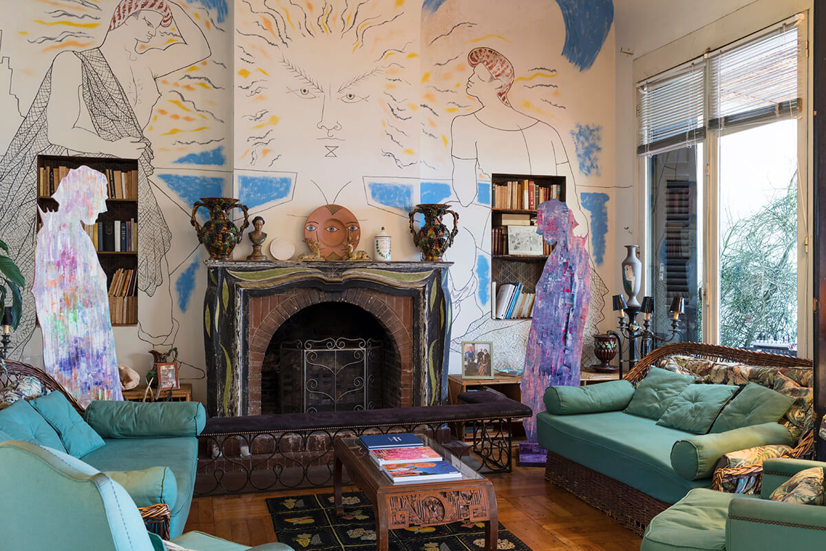 artistically decorated living room with large mural over fire place and two colourful sculptures standing either side
