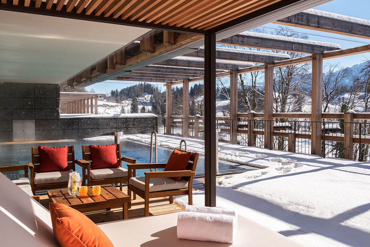 outdoor pool surrounded by snow with steam rising and plush surrounding sun loungers